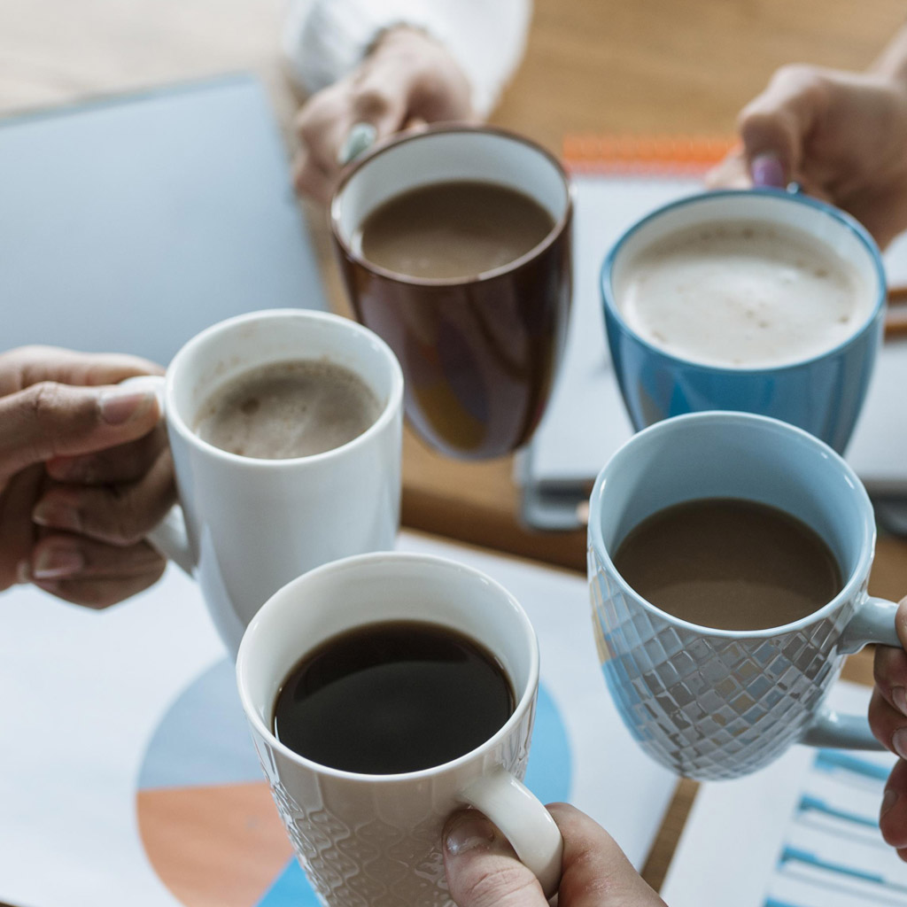 people holding up coffee cups